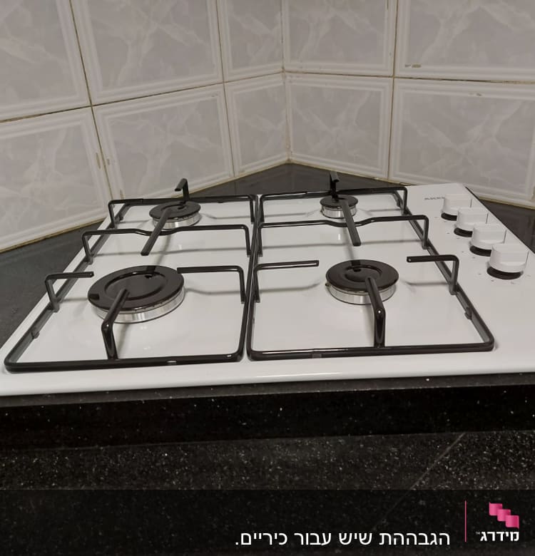 משטח שיש שחור ליד כיריים לבנות